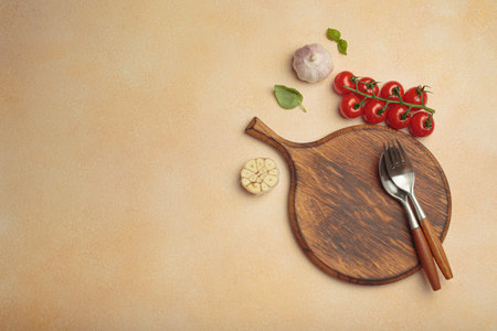 Food background with wooden cutting board, tomatoes, garlic, fresh basil and spices on light beige table, space for textの写真素材