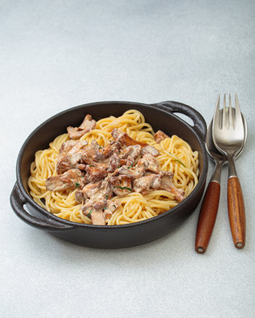 Creamy chanterelle mushroom pasta in cast iron pan with fork and spoonの写真素材