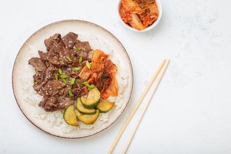 Korean beef bulgogi bowl dish with rice, roasted meat, kimchi and marinated cucumber on white background top view with chopsticks, space for textの写真素材