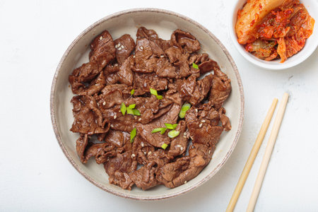 Bulgogi, grilled marinated beef Korean dish with kimchi and sesame seeds top view on white backgroundの写真素材