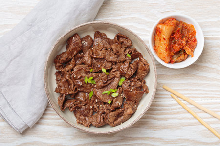 Bulgogi, grilled marinated beef Korean dish with kimchi and sesame seeds top view on white wooden backgroundの写真素材