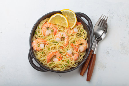Delicious seafood pasta spaghetti with shrimps dish garnished with lemon and parsley top view on white backgroundの写真素材