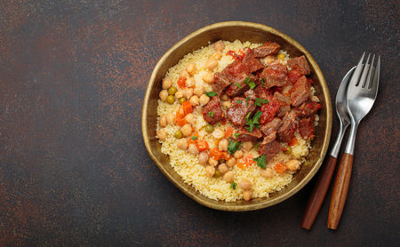 Moroccan couscous with tender meat and chickpea stew in rustic bow top view, Maghreb cuisine, space for textの写真素材