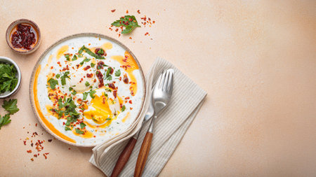 Turkish eggs cilbir, Middle Eastern style breakfast on beige background table top view, space for textの写真素材