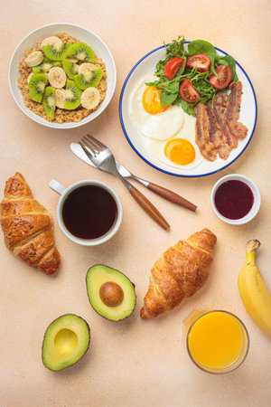 Breakfast warm beige background eggs vegetables salad, oats fruit, croissants, coffee, juice healthy morning.の写真素材