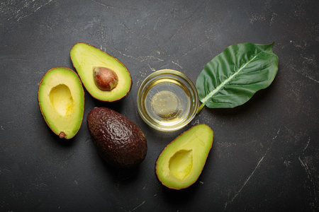 Avocados halves whole oil dark background healthy eating diet nutrition fat
