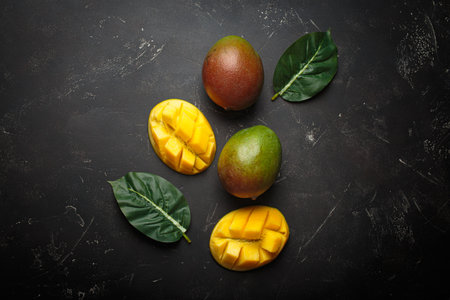 Ripe tropical sliced whole mangoes leaves dark background healthy exotic fruitの写真素材