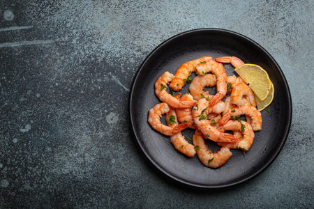 Cooked grilled shrimps lemon parsley black plate seafood appetizer black background copy spaceの写真素材