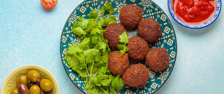 Falafel with tomato sauce, green olives and coriander leaves on blue background top viewの写真素材