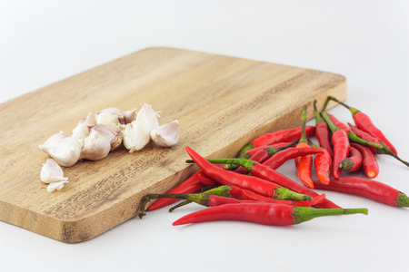 group of red chili and garlic with chopping block in white backgroundの写真素材