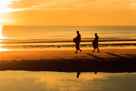 Silhouette of monk walking on Huahin beach in the morning , Thailandの写真素材