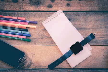 paper note and mobile phone on wood background in vintage styleの写真素材