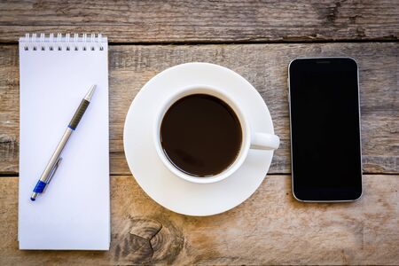 top view cup of coffee and smartphone with paper note on wood table backgroundの写真素材