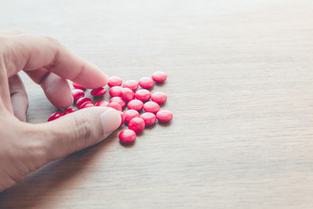 medicine pill on hand with wood table backgroundの写真素材