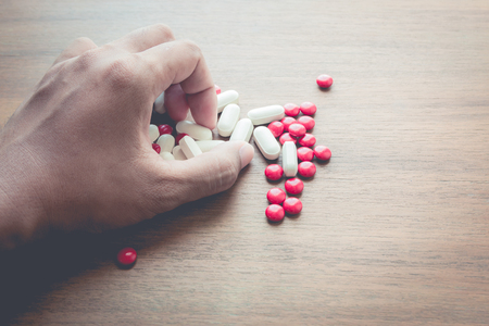 medicine pill on hand with wood table backgroundの写真素材