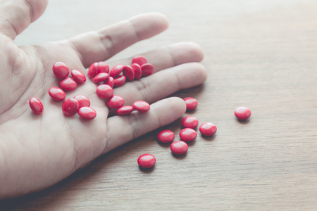 medicine pill on hand with wood table backgroundの写真素材