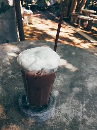 iced chocolate with cream and straw on tableの写真素材