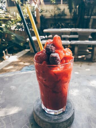 iced mixed berries smoothie and straw on tableの写真素材