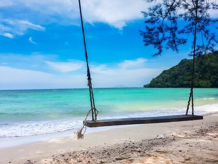 wooden swing hang from tree on beatiful sand beach and blue seaの写真素材