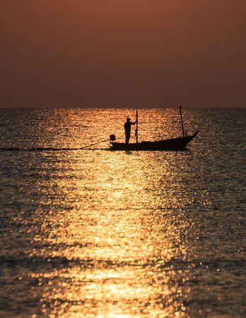 Silhouette of fishing boat and fisher man on sea in the morning,Huahin ,Thailandの写真素材
