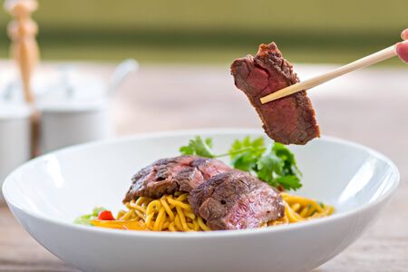 chopstick pick up beef from noodle bowlの写真素材