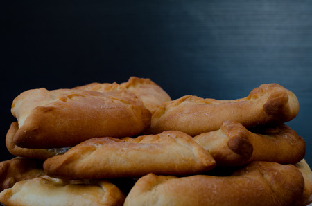 A plate with fresh pies on a black wooden table. Closeup