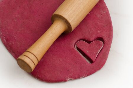 Sheet dough with red heart-shaped cut-out, preparing for Valentine's Dayの写真素材