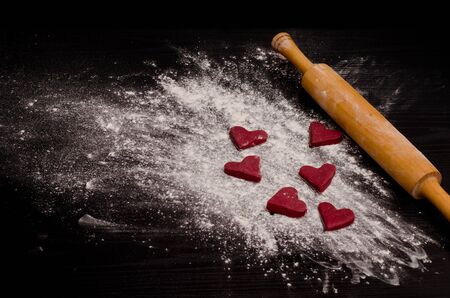 Red heart-shaped cookies on a flour, baking the day of Valentine's Dayの写真素材