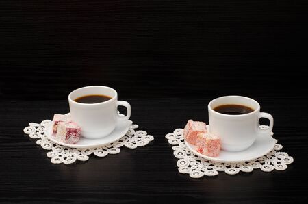 Two cups of coffee on the lace napkins and  turkish dessert on a black backgroundの写真素材