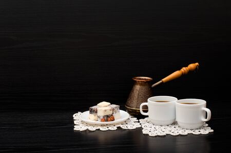 Rahat lokum and two cups of coffee on white napkins, pots on a black background. Space for textの写真素材