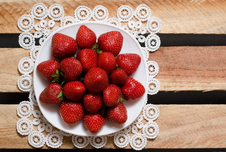 Ripe strawberries on a plate on wooden plates, a top view, space for textの写真素材