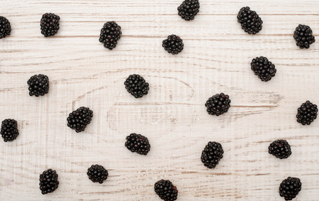 Scattered blackberries on a wooden light backgroundの写真素材