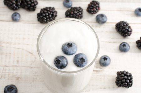 Blueberries in yogurt, berries on the table, light wood backgroundの写真素材