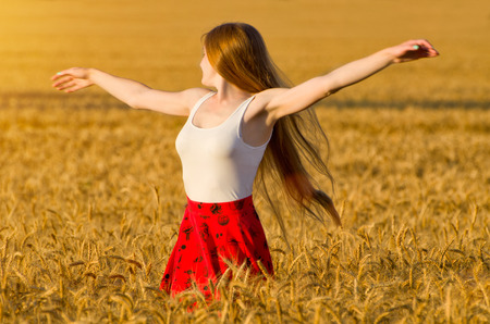 Girl turned her arms outstretched in a wheat fieldの写真素材