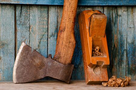 Old ax, planer and shavings on a blue wooden backgroundの写真素材