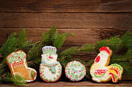 Gingerbread: sock, snowman, ball and cock, spruce branch on the background of wooden wall