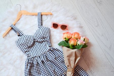 Fashion concept. Summer dress into a cell, pink glasses and a bouquet of roses. View from aboveの写真素材