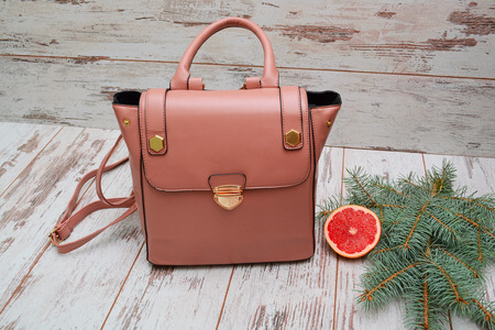 Fashion concept. Pink lady's bag on a wooden background, spruce branch and grapefruitの写真素材