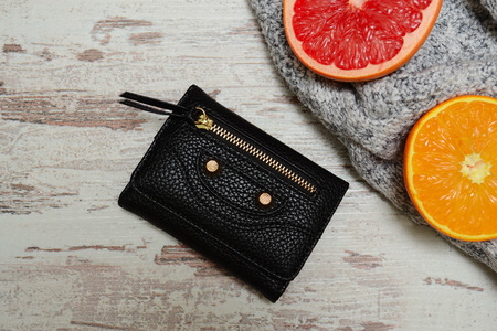 Fashion concept. Little black women's purse, and citrus on a sweater, a wooden background. View from aboveの写真素材