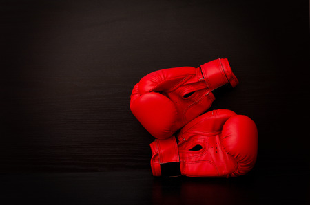 Red boxing gloves on a black background in the corner of the frame, place for textの写真素材