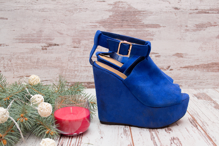Blue suede shoes on a wooden background, fir branch, garland and candle. fashion conceptの写真素材