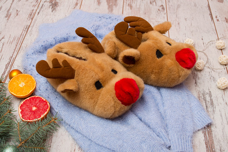 Soft slippers-deer on a blue sweater, spruce branch, citrus fruits and a garland on a wooden backgroundの写真素材