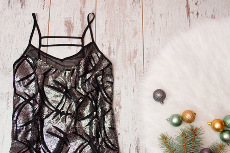 Black dress in a blaze on a wooden background, Christmas balls on white fur. Fashionable concept, top viewの写真素材