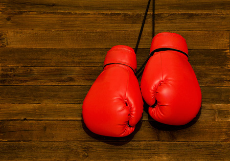 Two red boxing gloves hung on a wooden brown background, empty spaceの写真素材