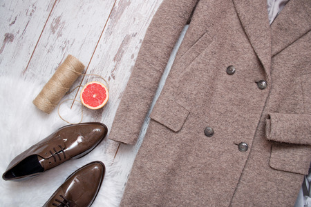 Brown coat and brown patent leather shoes on a white fur, grapefruit and twine, wooden background. Fashion concept. top viewの写真素材