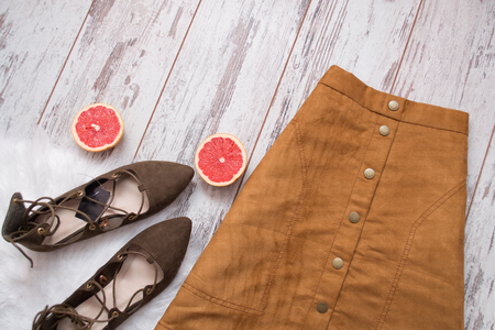 Brown suede skirt, brown suede shoes, cut grapefruit halves. Wooden background. Fashion concept. top viewの写真素材