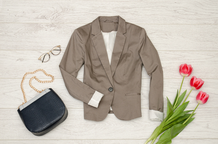 Fashion concept. Classic jacket, handbag, sunglasses and pink tulips. Top view, light wood backgroundの写真素材