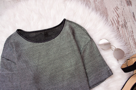 Blouse of metallic color and glasses on white fur. Fashionable concept, top view