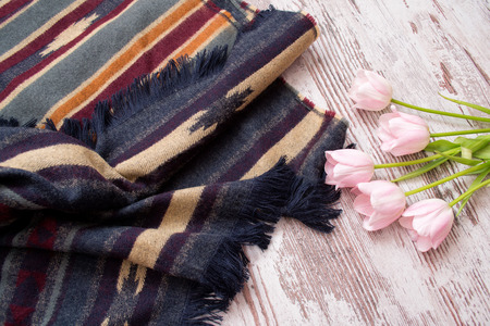Part of the scarf in stripes and ornament, pink tulips. Light wooden background