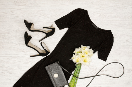 Black dress, shoes, clutch and a bouquet of daffodils. Fashionable concept. Wooden background.の写真素材